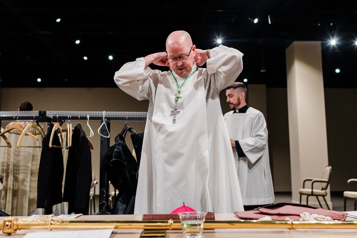 A person in white religious robes performs a ceremonial blessing or ritual at an altar during a church service.