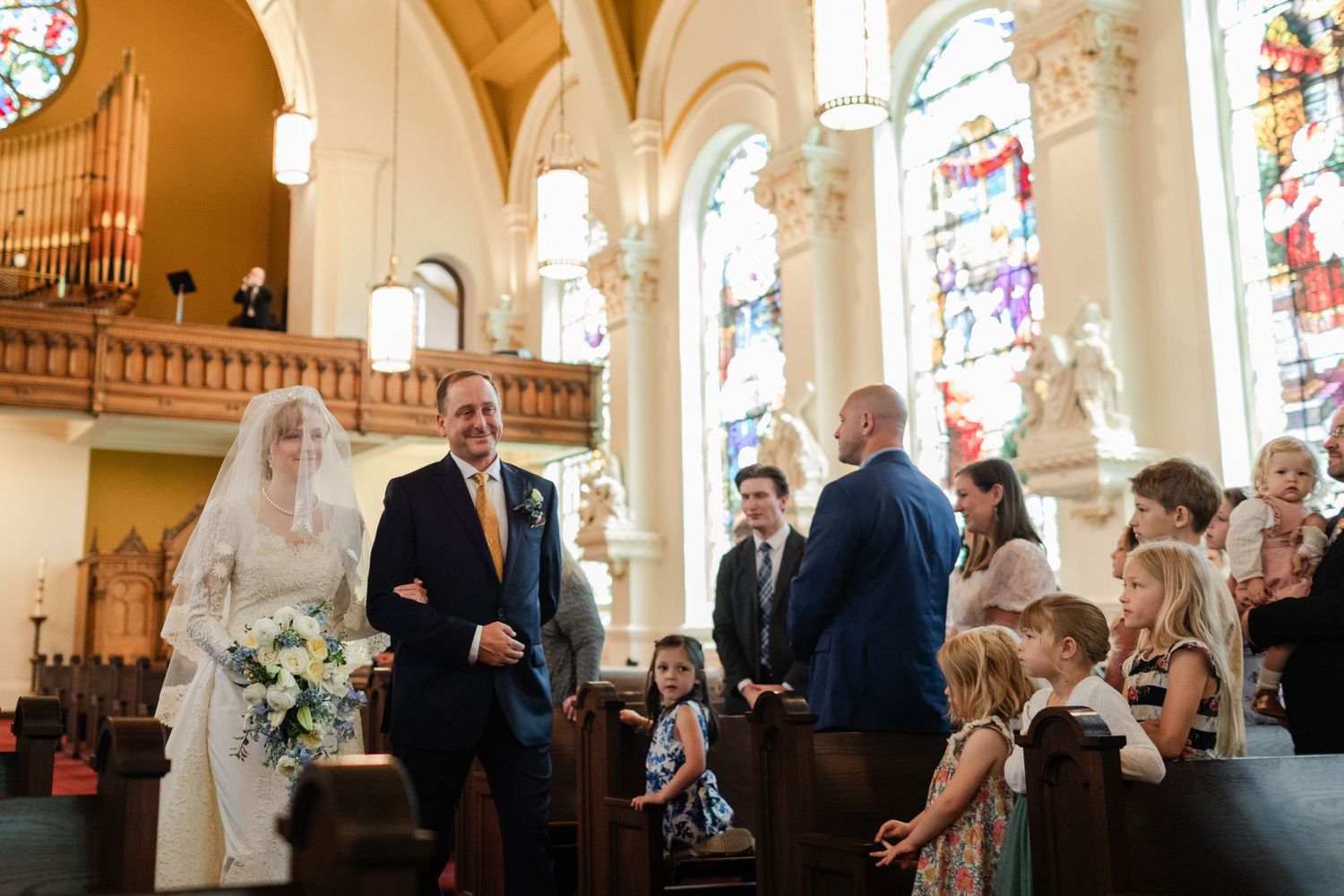 Bride and groom share a joyful moment walking down the aisle of an elegant church during their wedding ceremony.