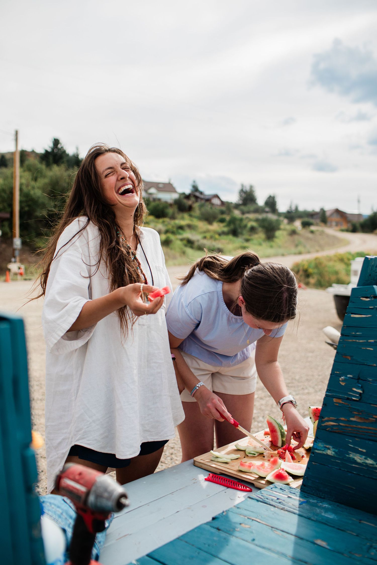 People enjoying a casual outdoor meal at a blue picnic table on a sunny day.