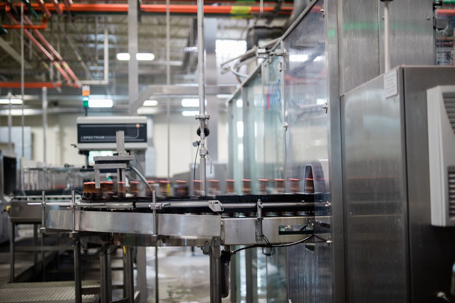 Modern industrial factory interior with automated machinery and equipment visible through glass partitions.