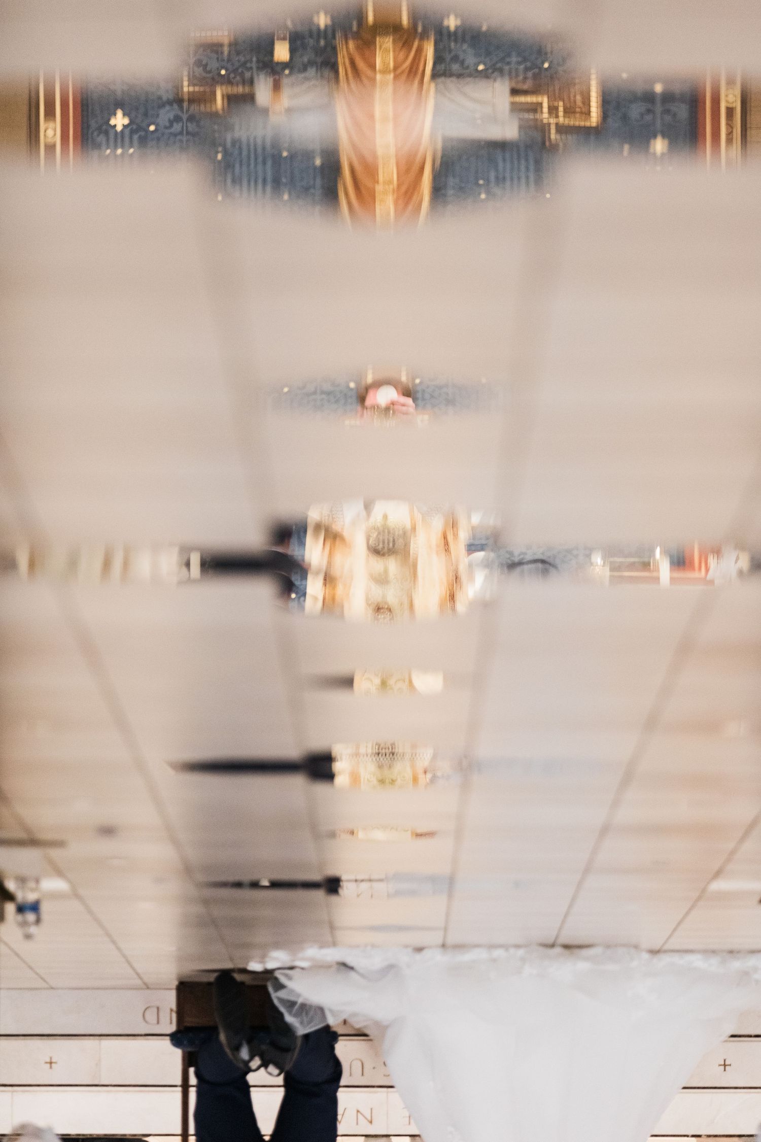 Artistic reflection of bride and groom in church during wedding ceremony captured in floor surface.