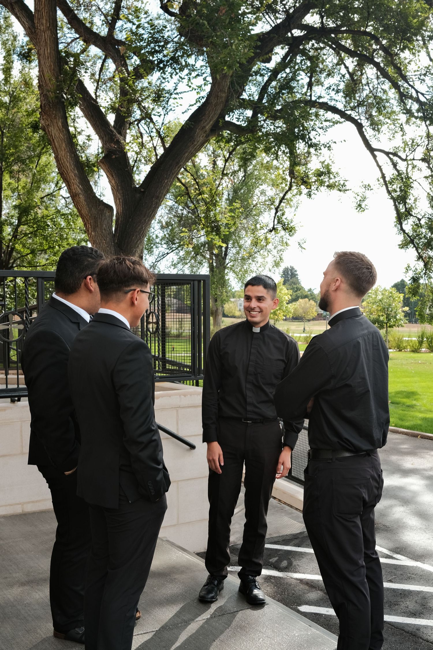 A sequence of images showing groomsmen in black suits standing together outdoors on a sunny day.