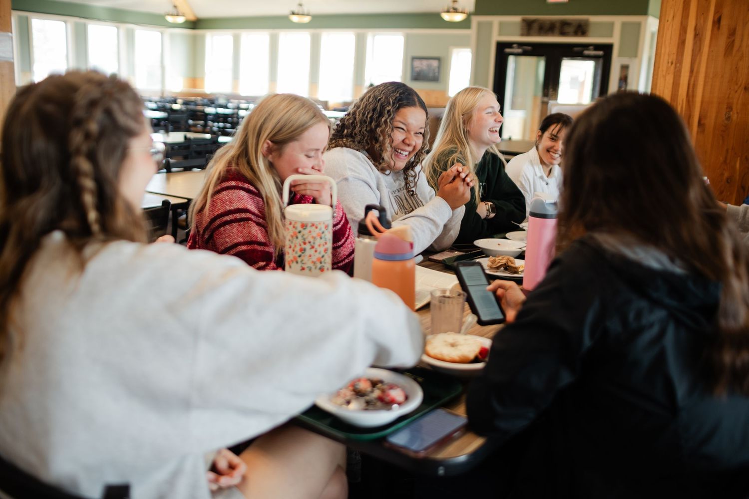Students sit at tables in a classroom while working together on an academic assignment.