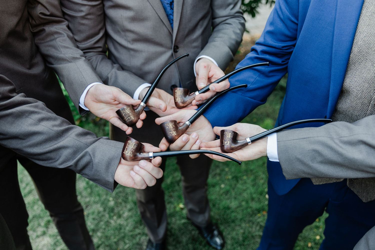 Group of men in suits holding smartphones together in a circle, showcasing modern technology at a formal event.