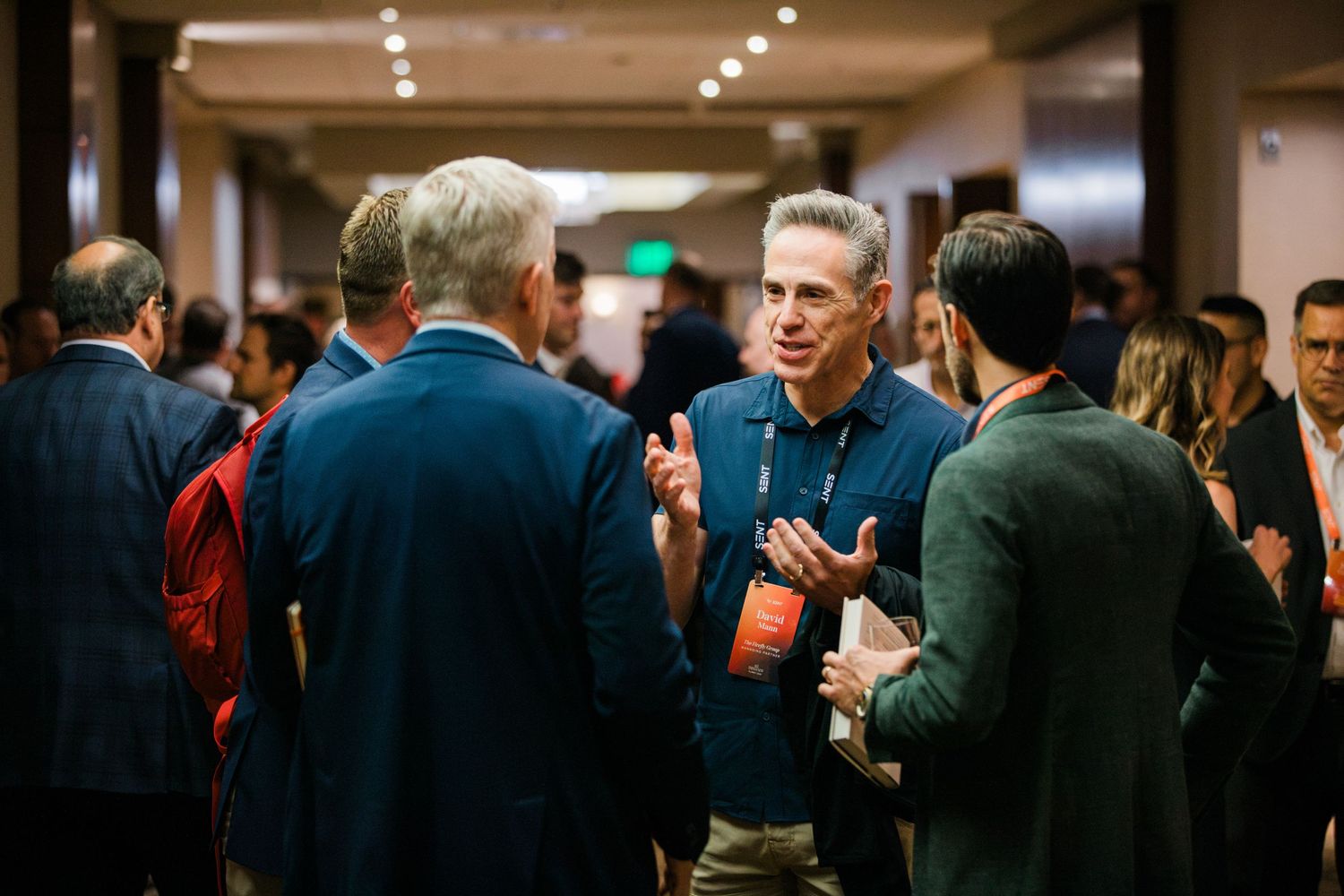 Professionals networking at a corporate event, engaged in conversation in a well-lit conference hall.