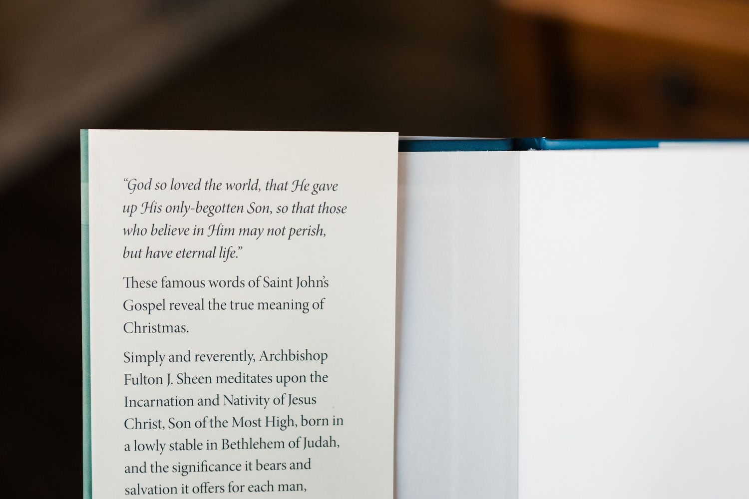 Close-up view of an open book with text visible on white pages against a blurred dark background.
