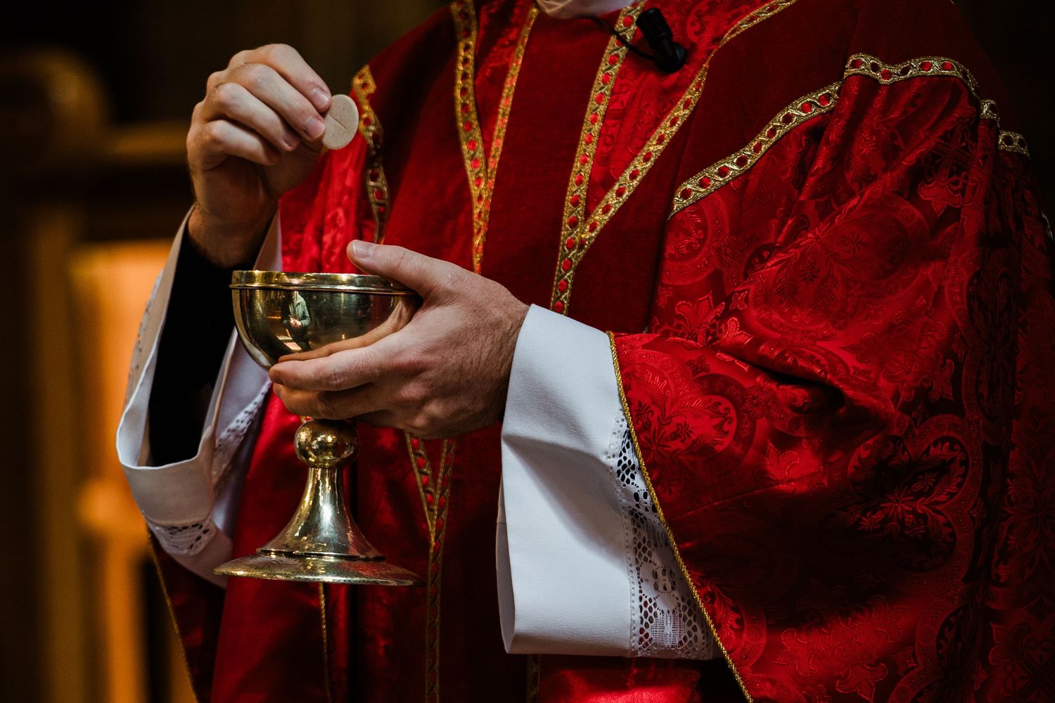 Close up shot of hands holding a golden chalice during a religious ceremony.