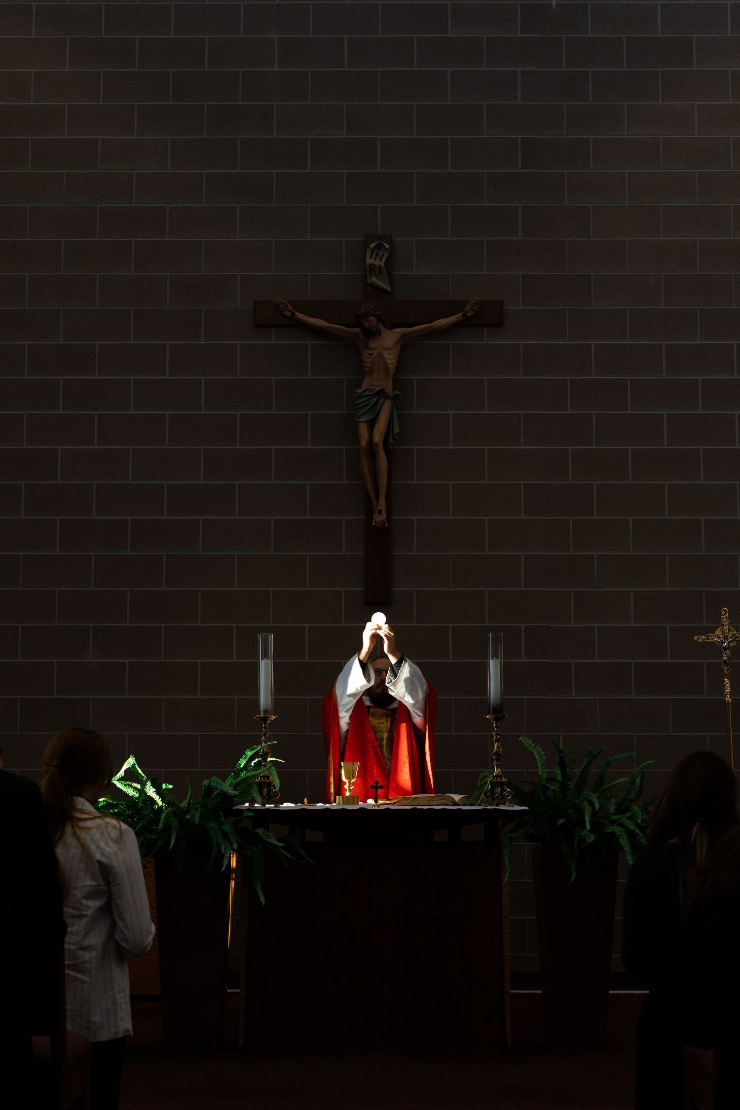 A dimly lit altar with crucifix and candles creates a solemn religious atmosphere.