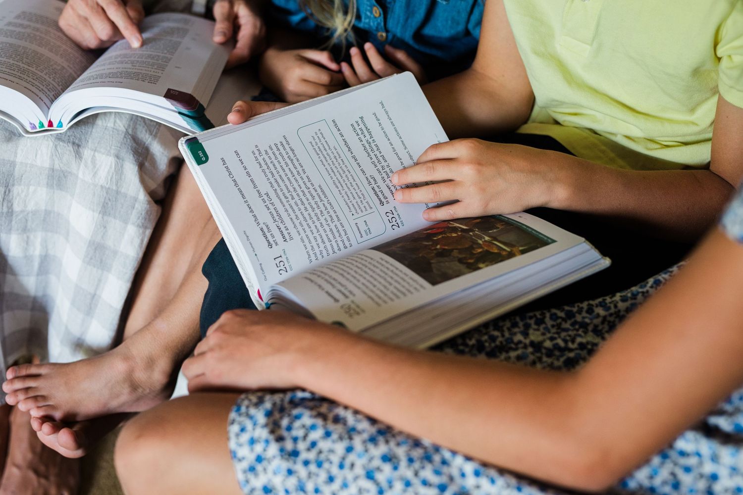 Two people sitting together reading open books indoors in a casual setting.
