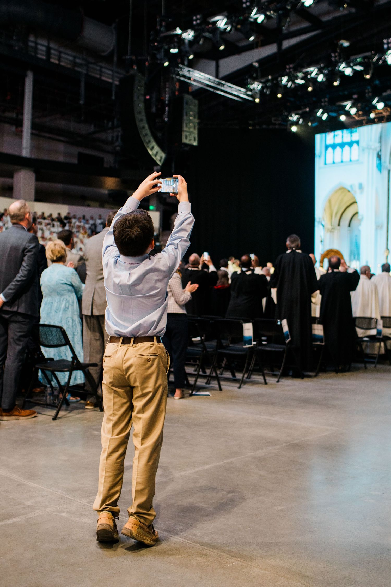 A sequence of photos showing someone in khaki pants taking photos at an indoor event venue with their phone.