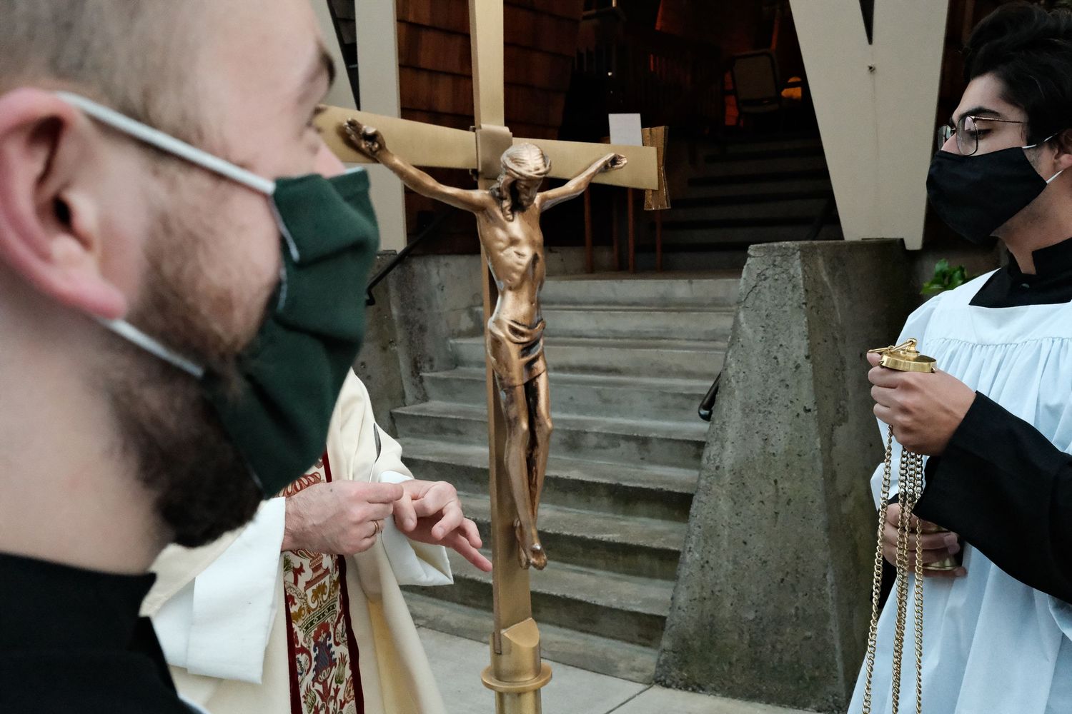 Four close-up shots show hands holding and focusing on a small golden crucifix in various positions.