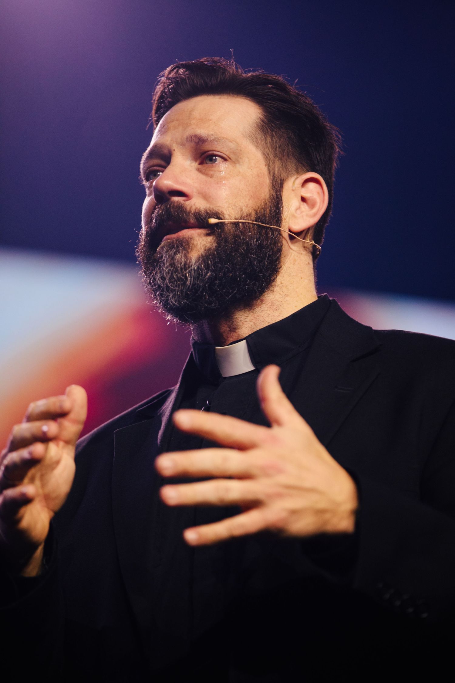 A close up sequence of a minister giving a passionate sermon with dramatic lighting.