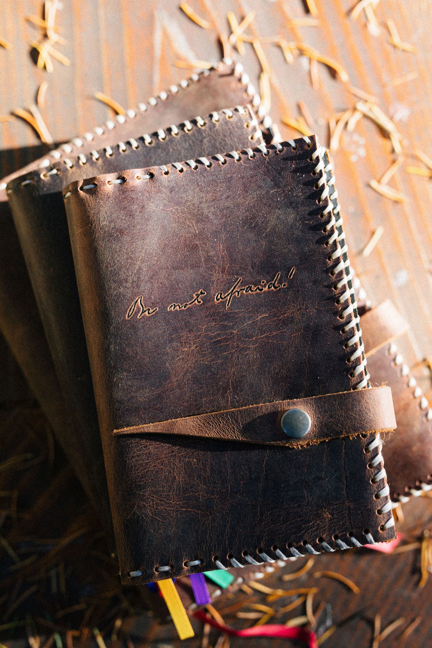Close-up photos of a dark brown leather wallet with whipstitch edges showing various angles and details against a textured surface.