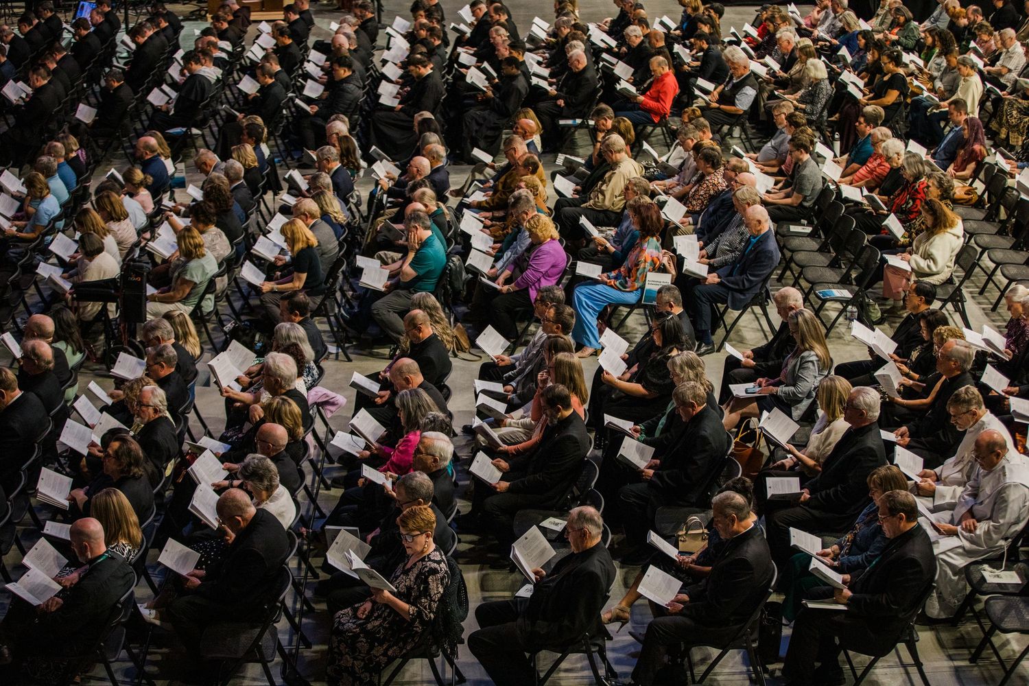 Large crowd of people sitting closely together in an auditorium or theater venue during an event.