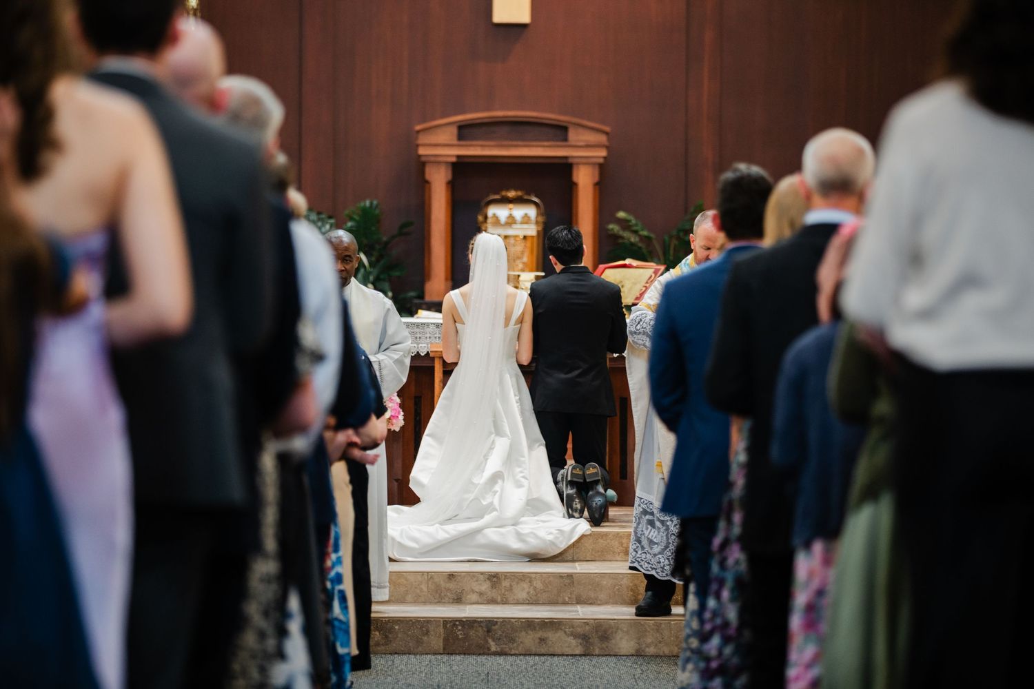 Wedding guests gather around a dance floor at an indoor reception venue during a celebration.