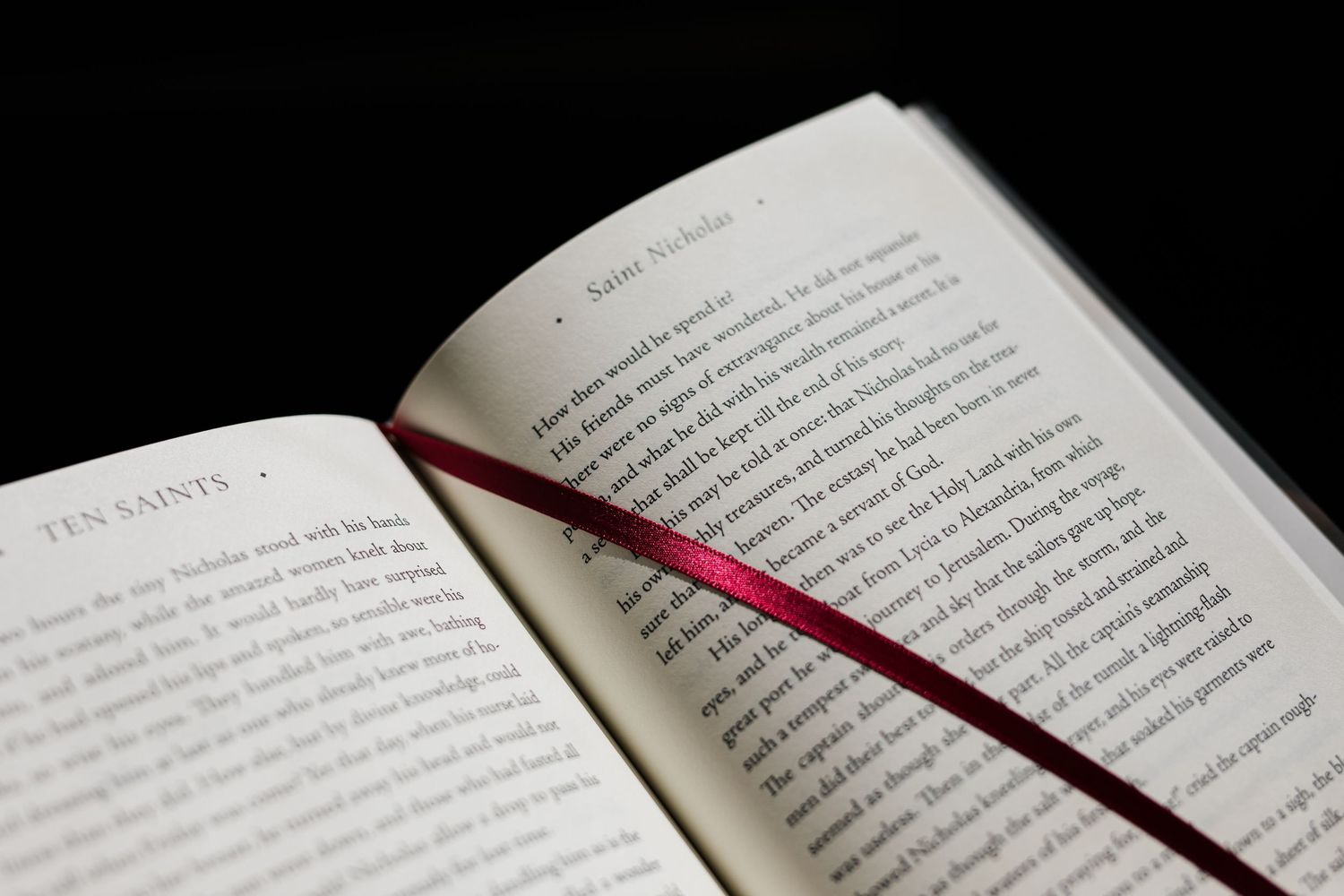 Open book with text pages illuminated against a dark background with dramatic lighting.