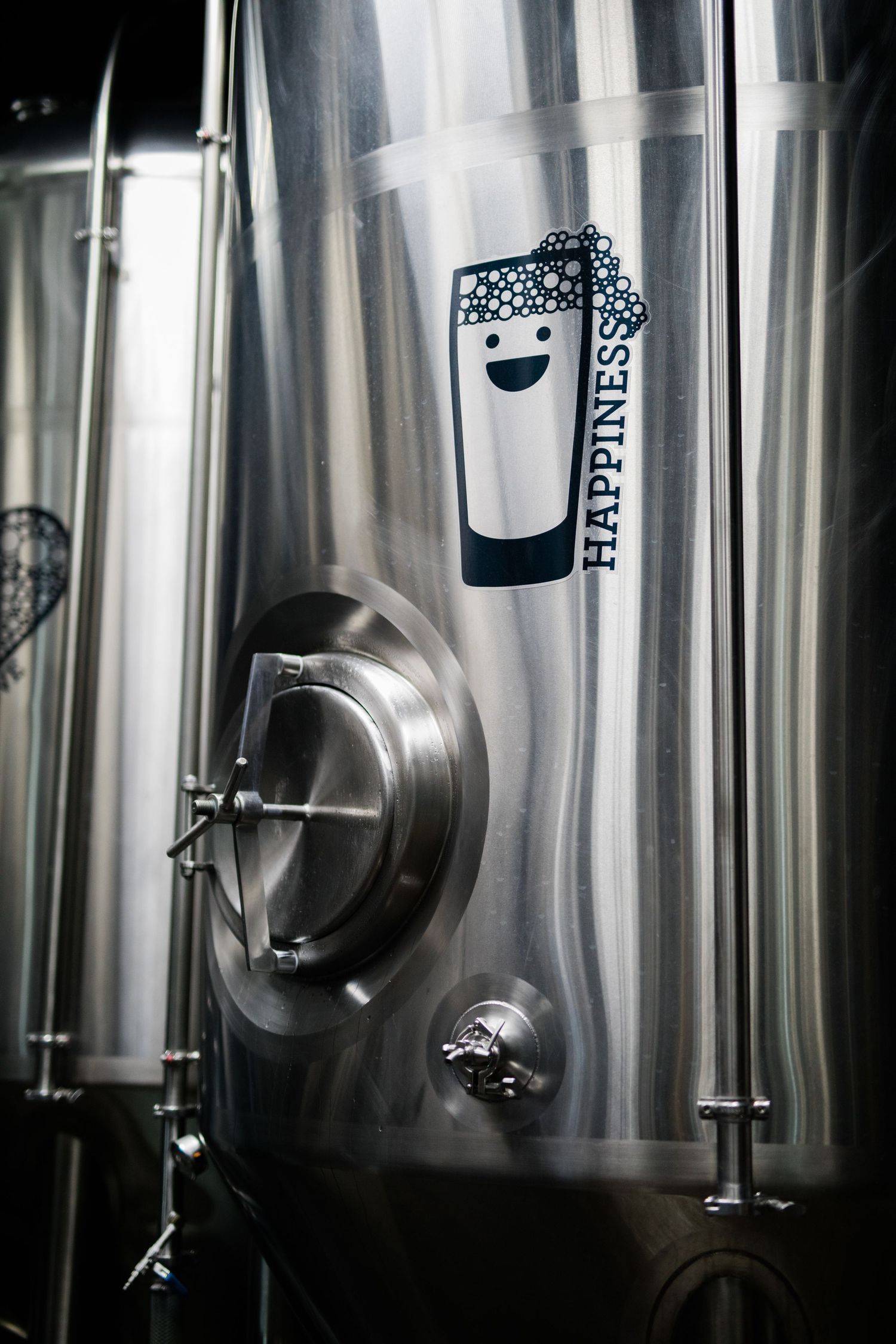 Stainless steel fermentation tanks in a modern brewery facility with industrial equipment and controls.