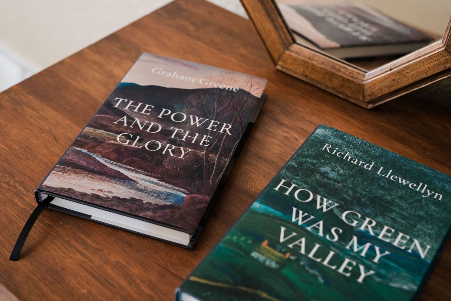 Two classic novels, The Power and the Glory and How Green Was My Valley, rest on a wooden table.