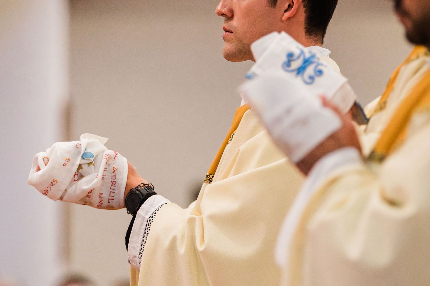 Catholic priests in golden vestments holding decorated chalices during a religious ceremony.