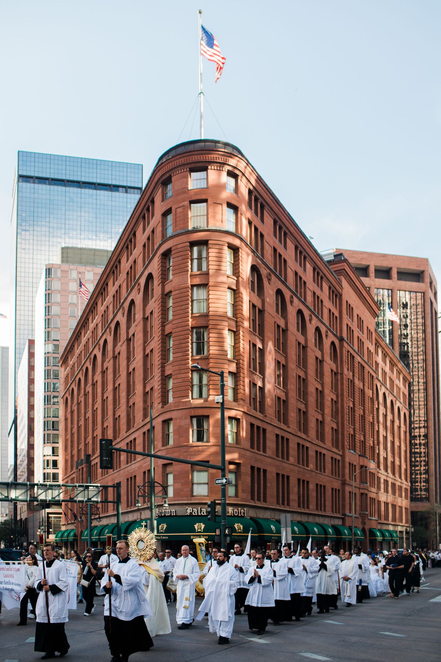 Religious procession marches past historic red brick Daniels and Fisher Tower in downtown Denver, Colorado.