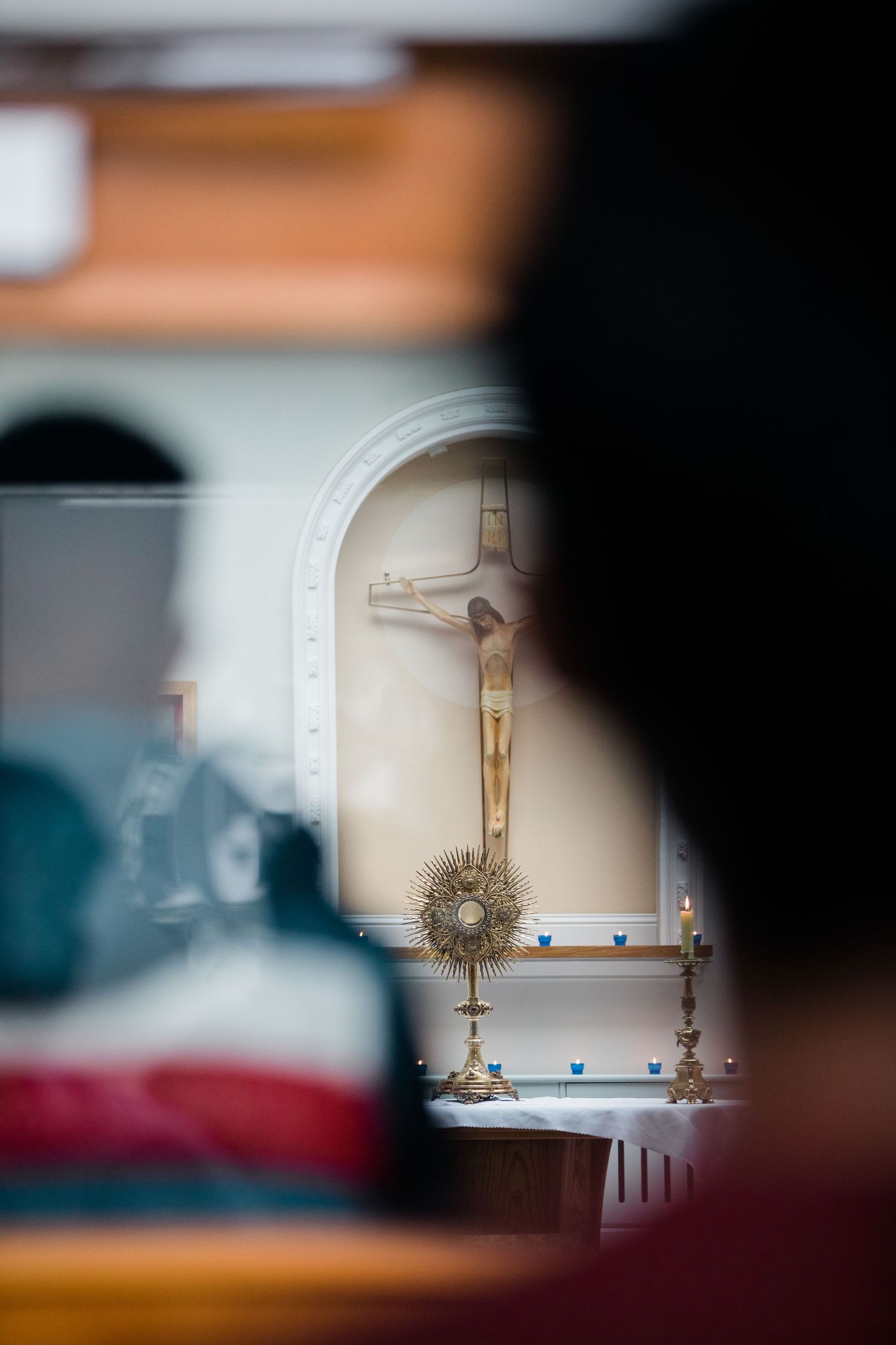 A Catholic monstrance on an altar with a crucifix in a church during adoration.