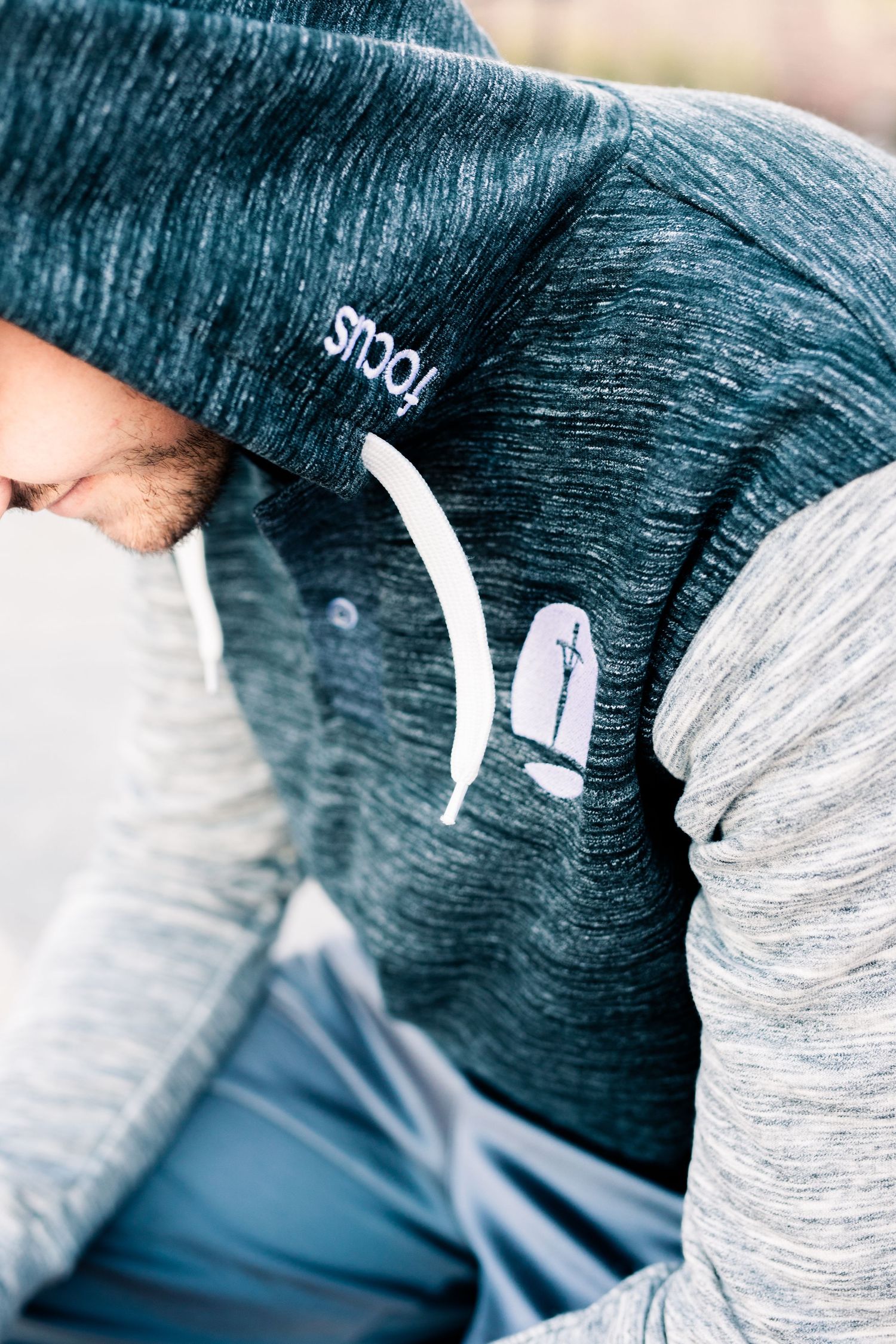 Close-up detail of heathered athletic wear showing text and simple design elements in a teal and gray color scheme.
