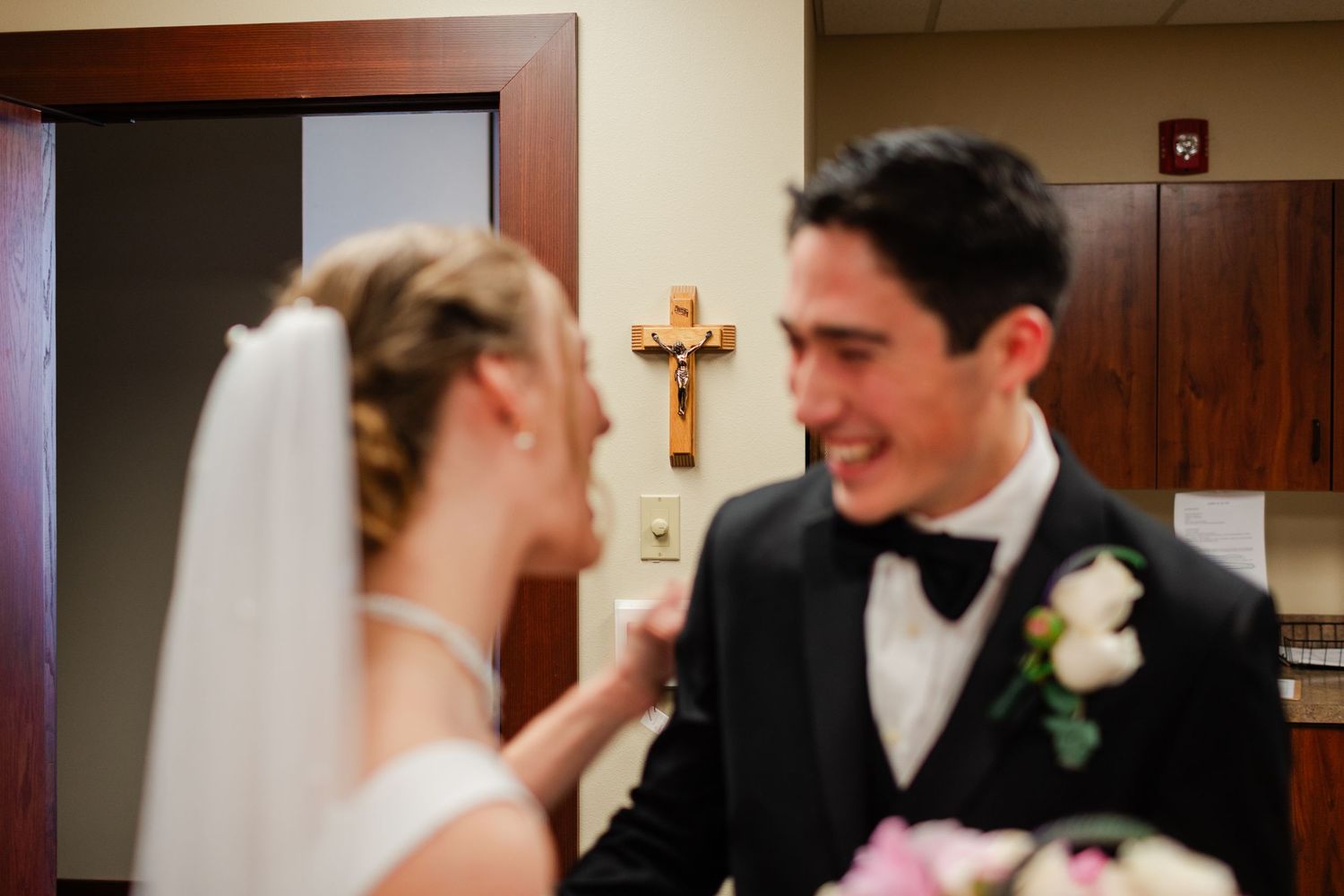 A wedding couple shares an intimate moment in a church hallway during their special day.