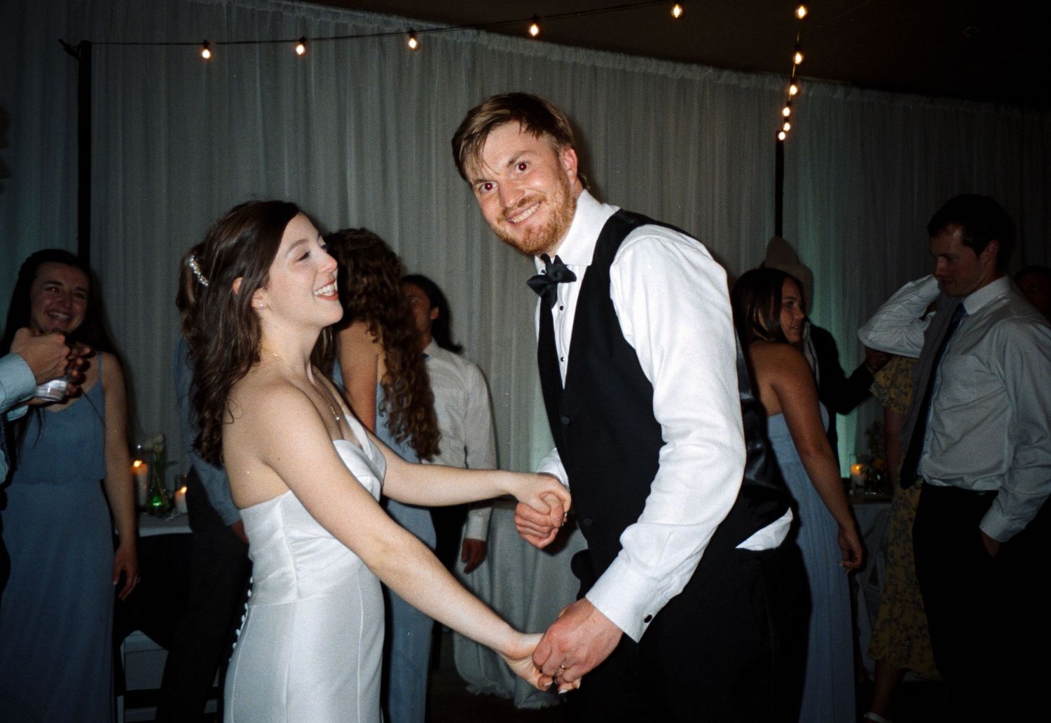 People dancing together at a wedding reception with dim lighting and festive atmosphere.