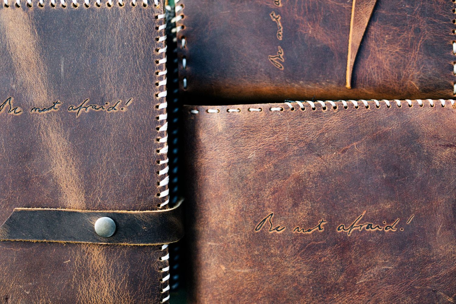 Close-up of stitched brown leather goods with 'Do not despair' inscribed in cursive text on vintage surface.