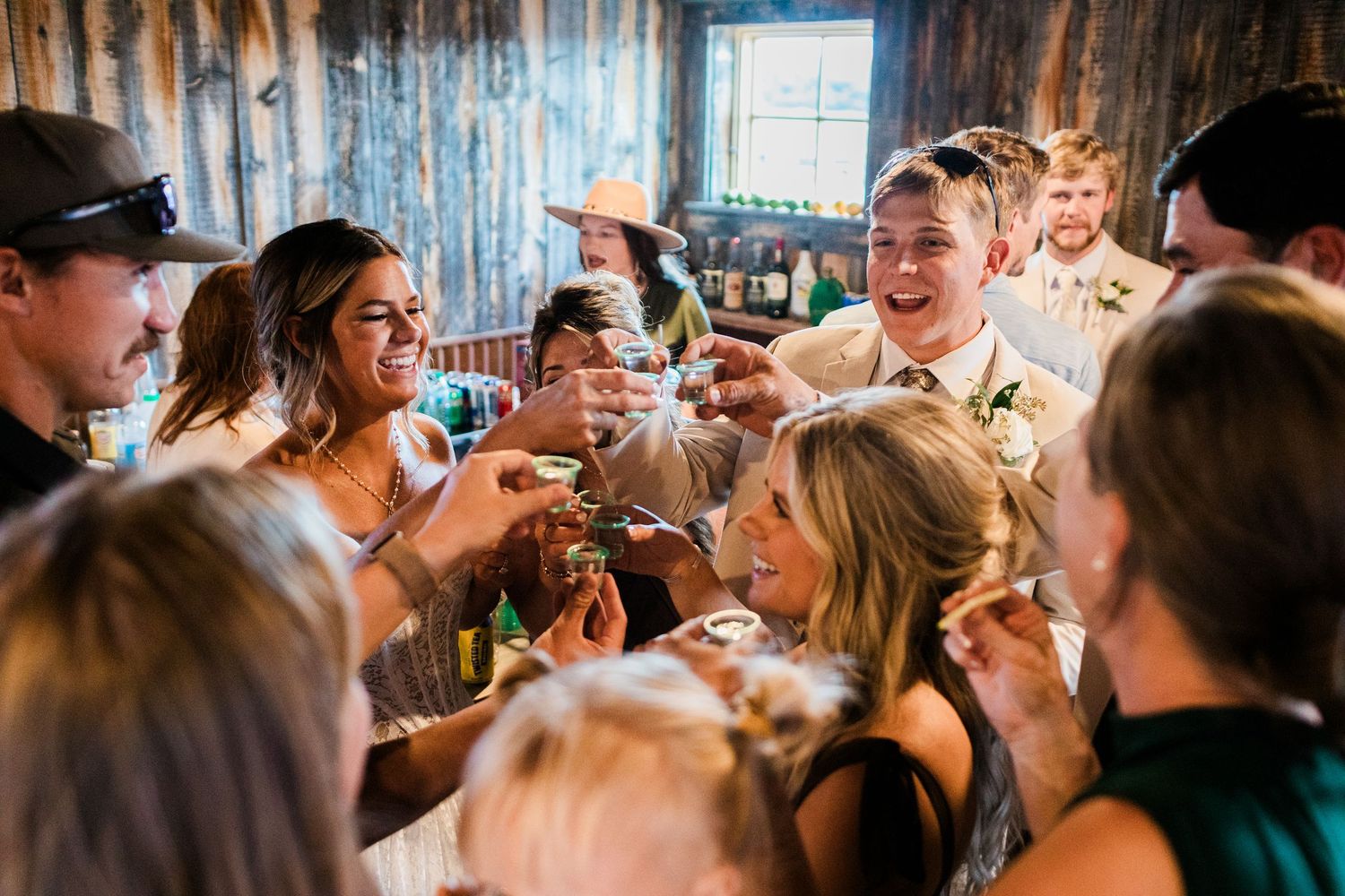 Wedding guests raising glasses in a joyful toast at a rustic barn reception celebration.