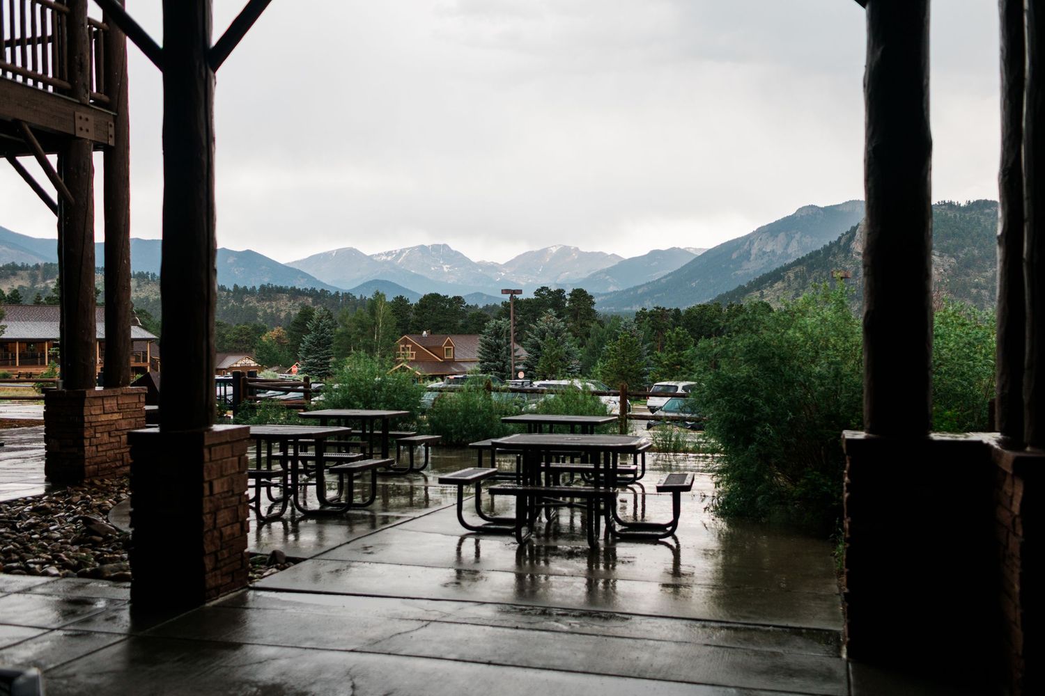 Wet outdoor patio with picnic tables overlooking misty mountain views on a rainy day.