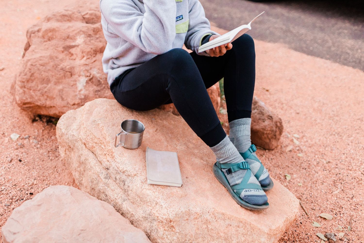 Close-up of hiking boots on red sandstone rock formations along a trail in a desert landscape.