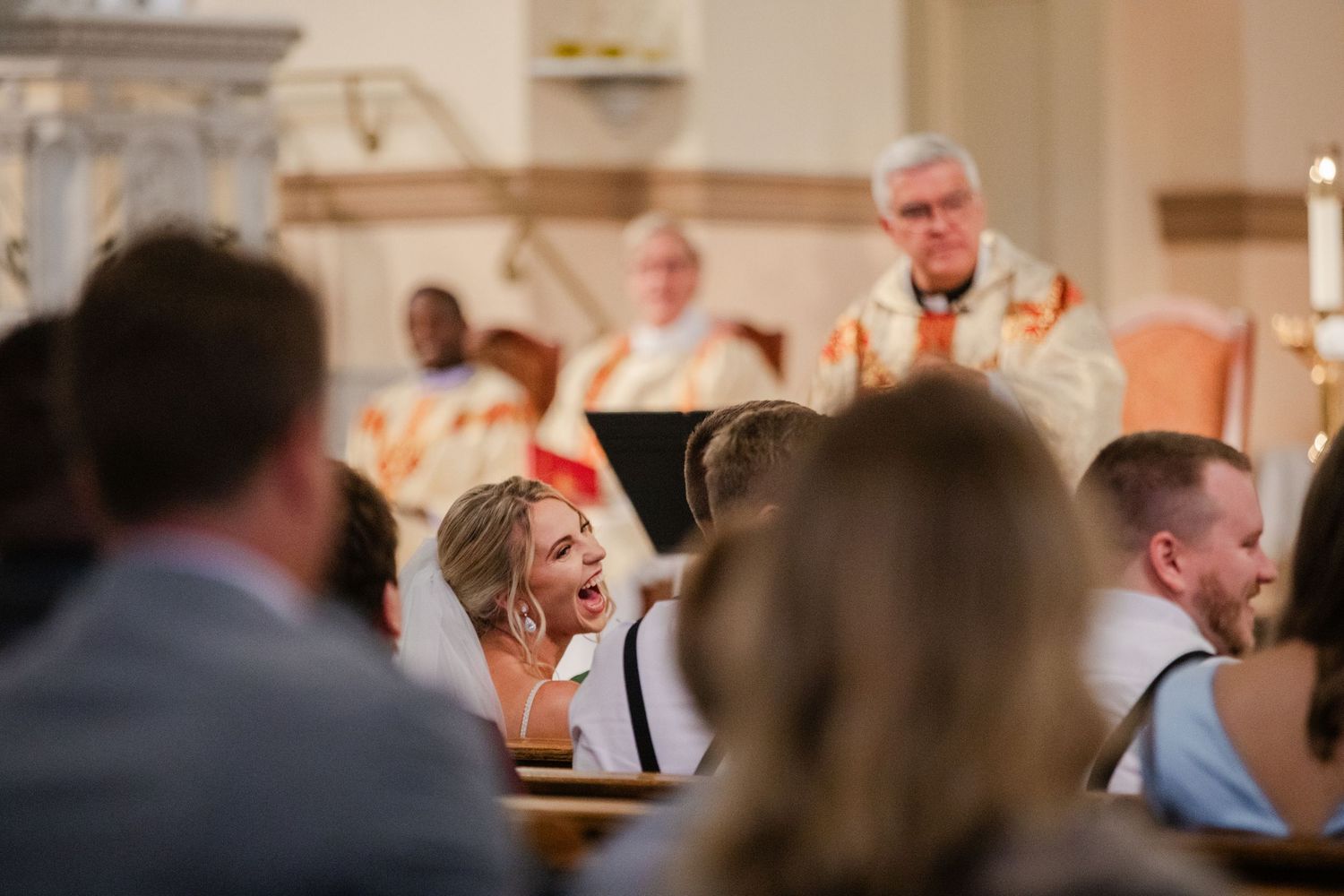 Wedding guest reacts emotionally during church ceremony with priest officiating at the altar.