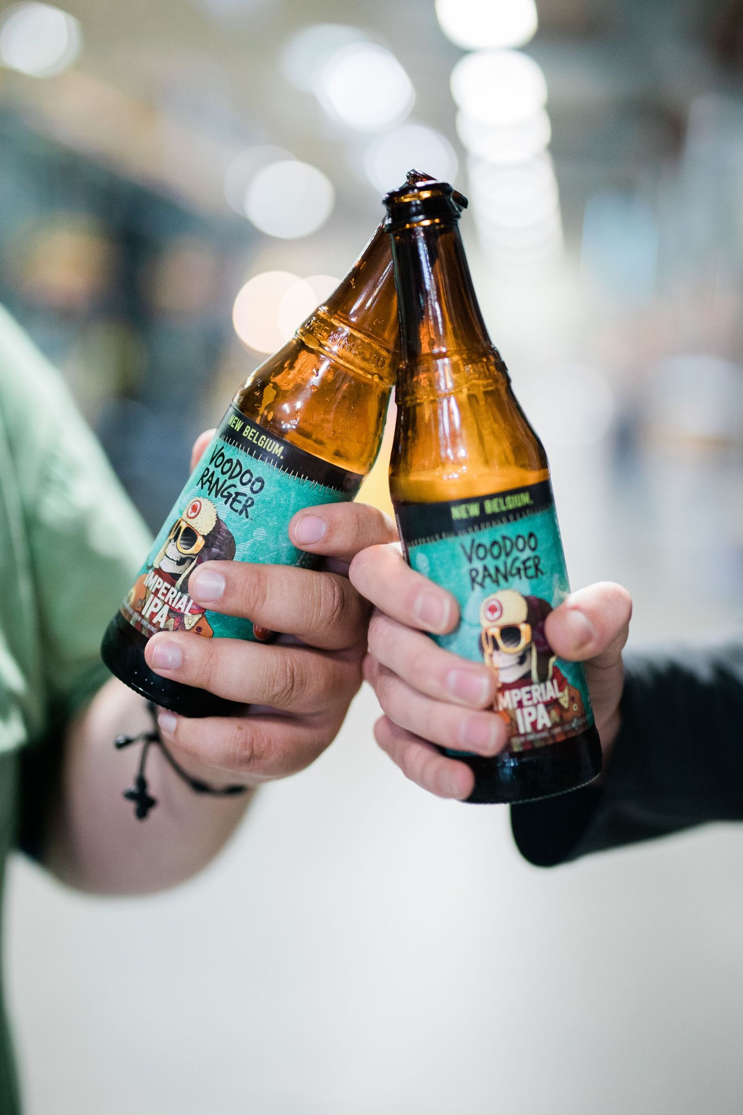 Two hands clink brown glass bottles of Flying Dog craft beer together in a celebratory cheers motion.