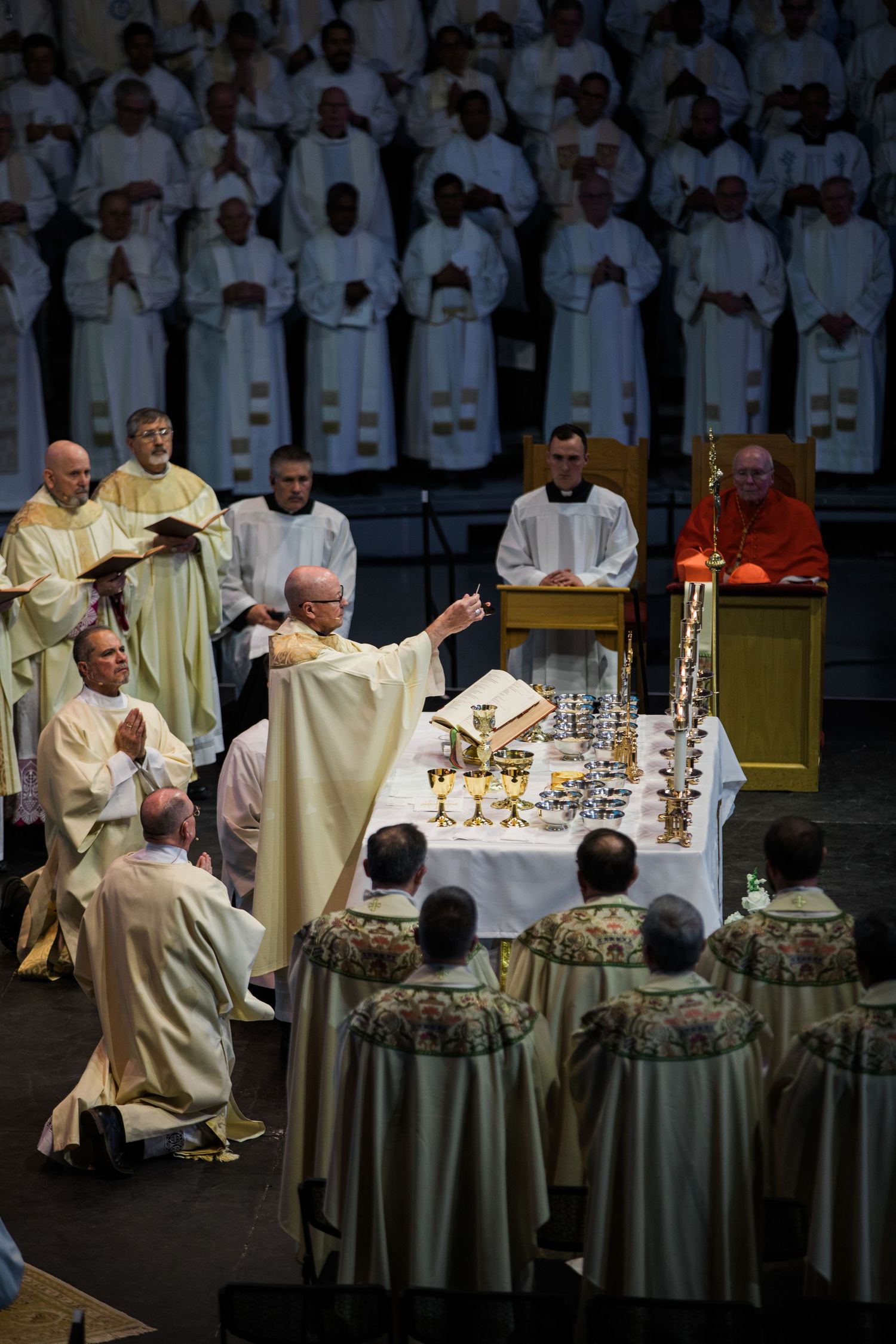 Religious ceremony showing priests gathered around altar table with ceremonial items during sacred ritual.