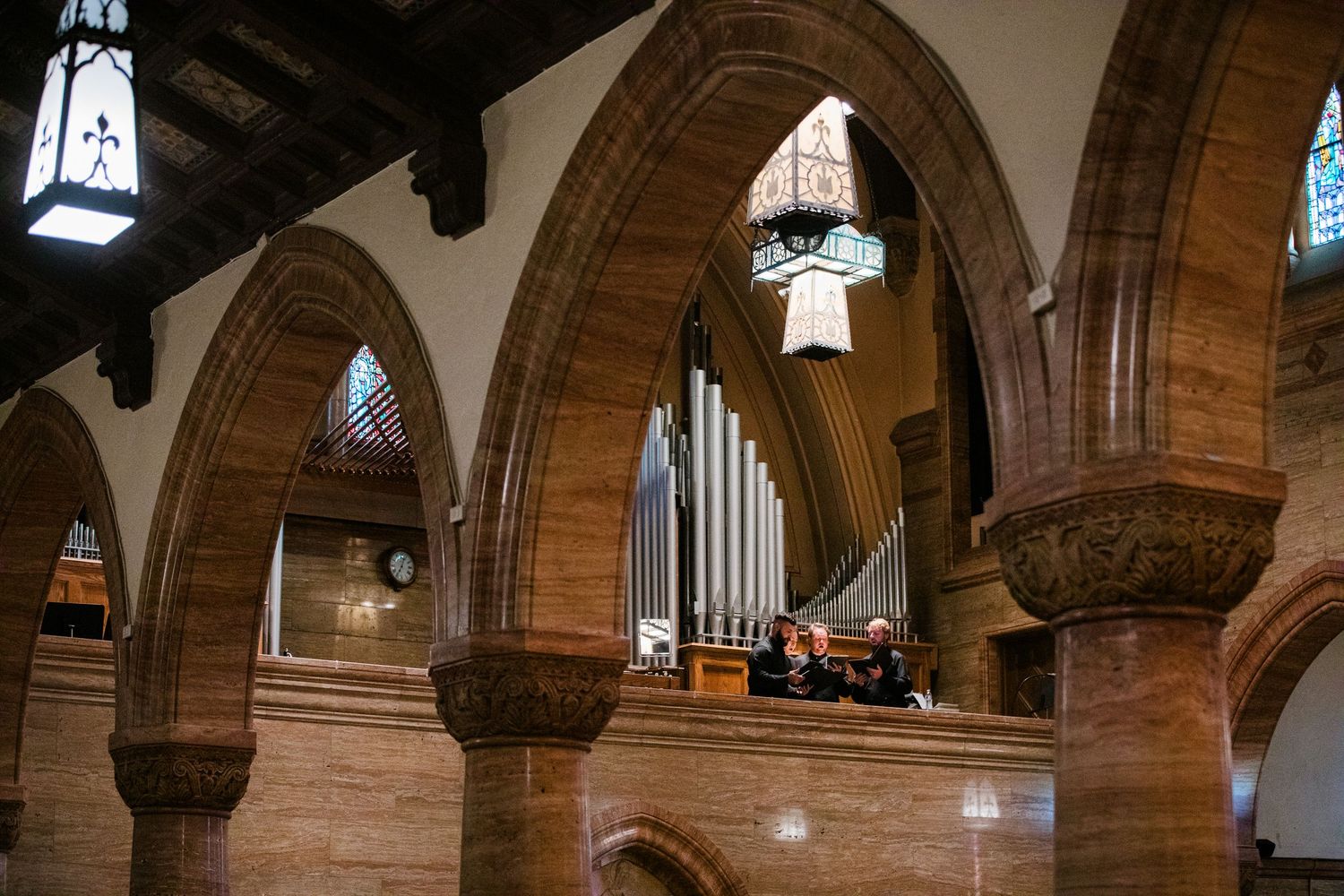 Historic church interior featuring ornate sandstone arches, pipe organ, and elegant stained glass windows.