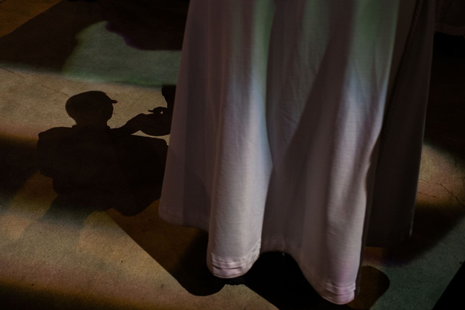White ceremonial robes cast shadows on church floor.