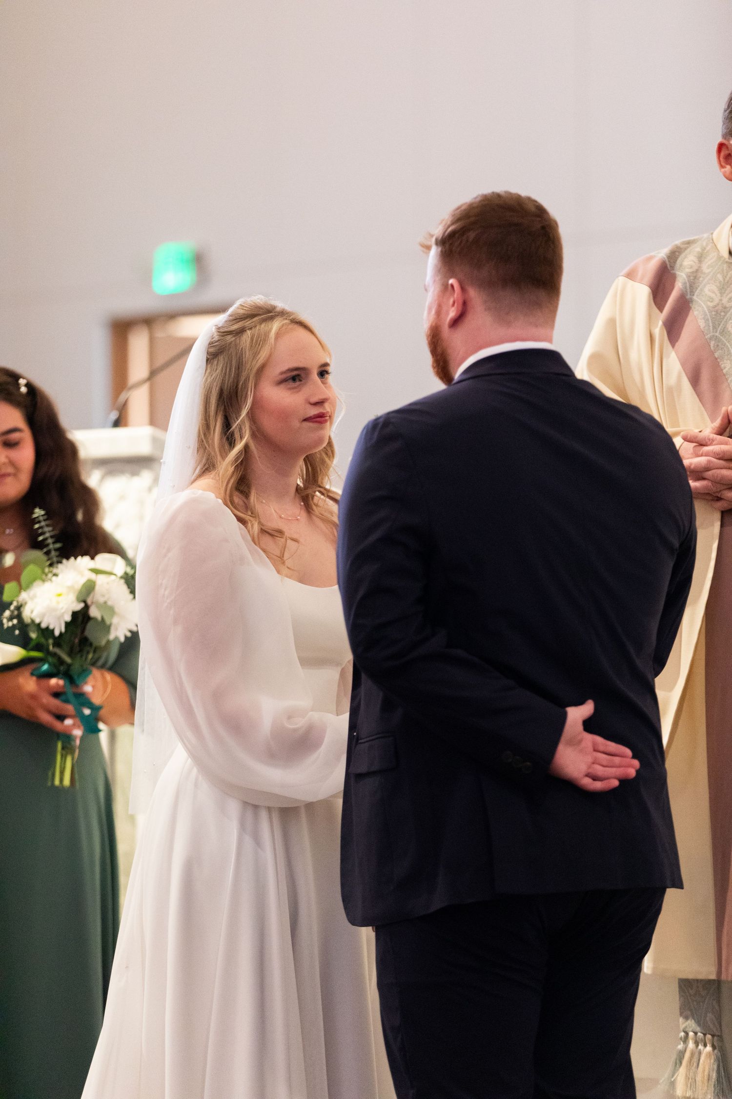 A couple shares a tender first dance moment at their wedding reception with guests watching in the background.