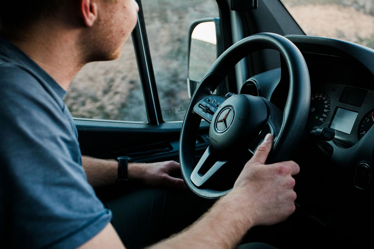 Close-up view of hands gripping a steering wheel while driving a vehicle.