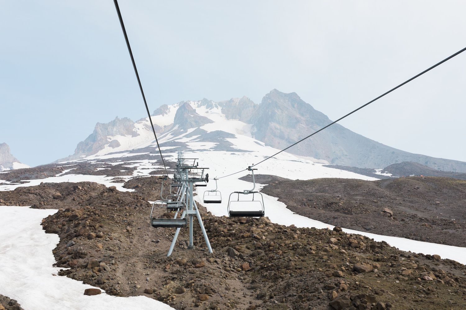 Panoramic view of a mountain landscape with ski lifts and snow-covered terrain against a clear blue sky.