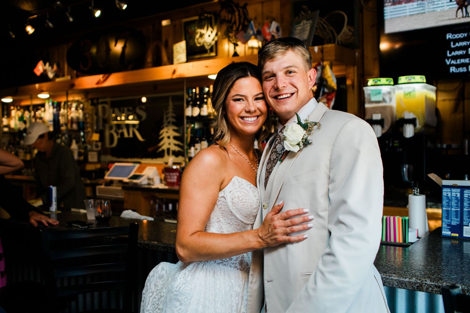 Happy bride and groom posing together in a rustic bar venue on their wedding day.