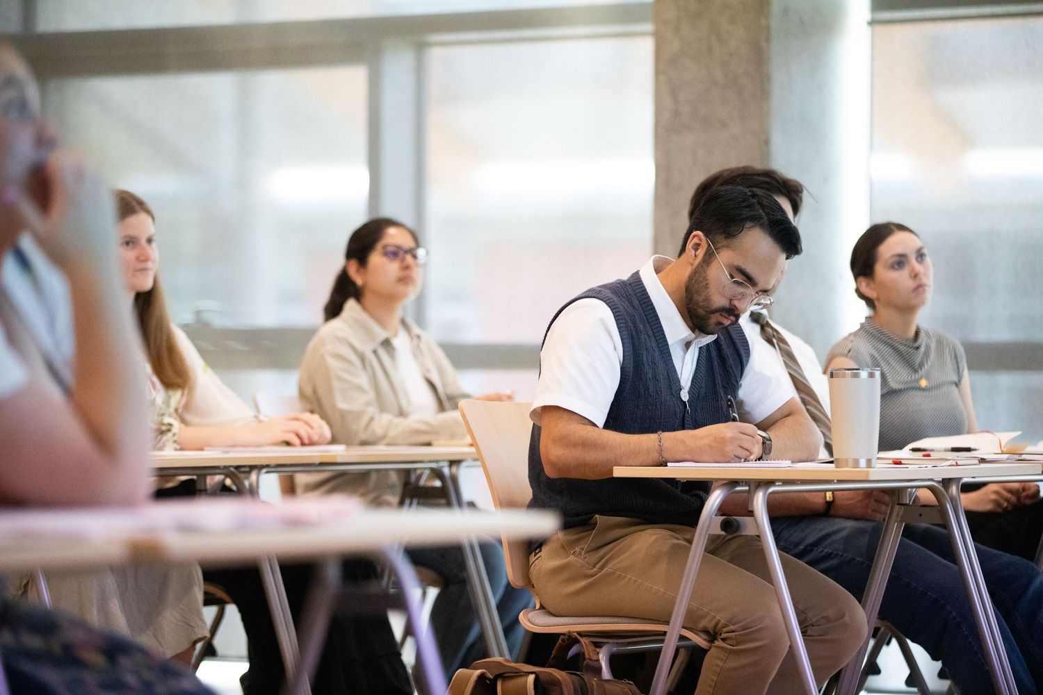 Diverse college students sitting at desks in a bright classroom during an exam.