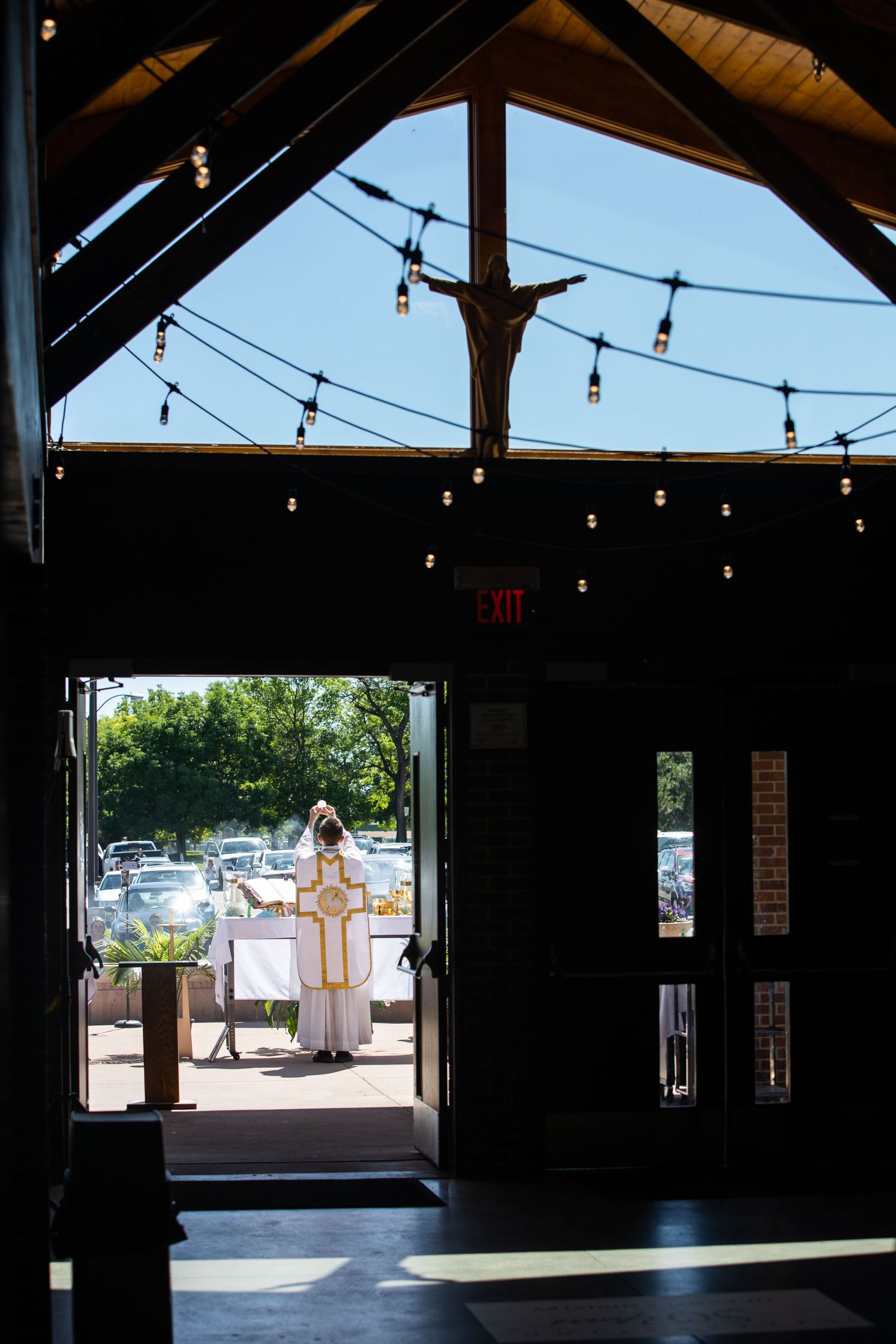 Interior view of an open pavilion with string lights and wooden beams overhead.