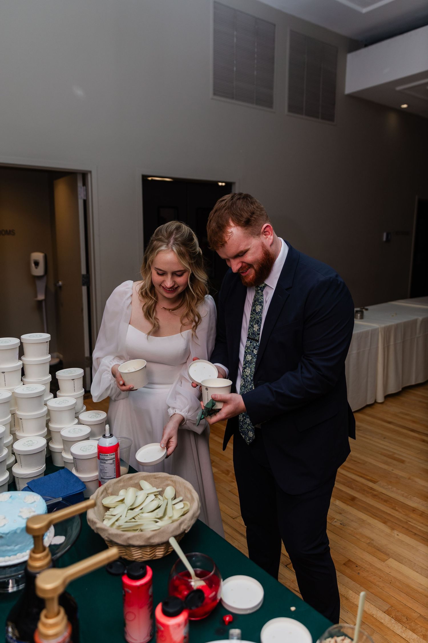 A couple sharing a joyful moment while cutting into their wedding cake at an indoor reception.
