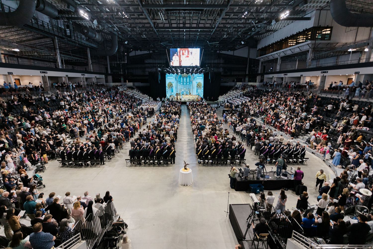 Aerial view of packed arena congregation attending a large-scale Catholic religious ceremony or Mass.