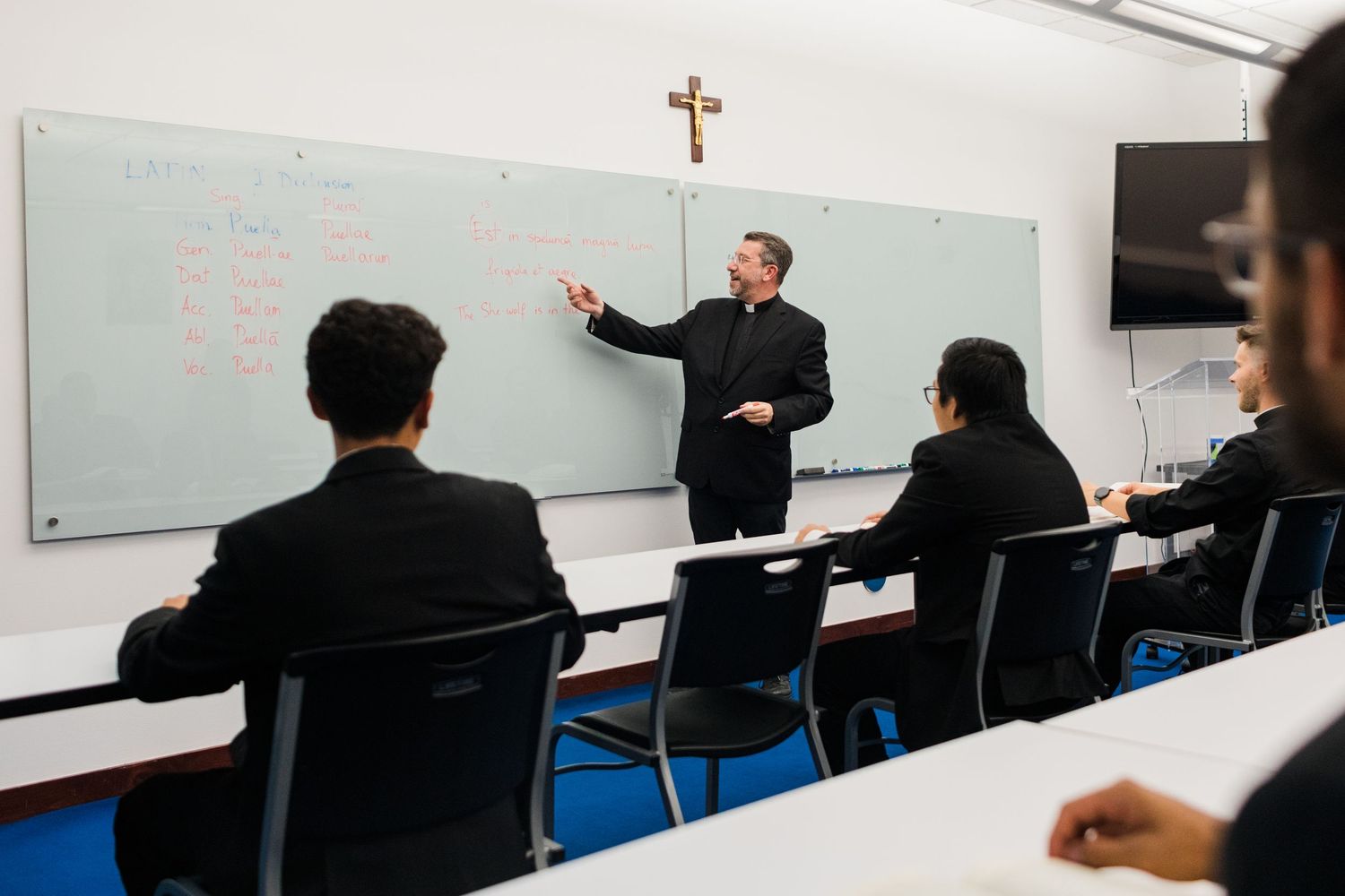 Students seated in rows at desks while attending a business presentation in a modern classroom.