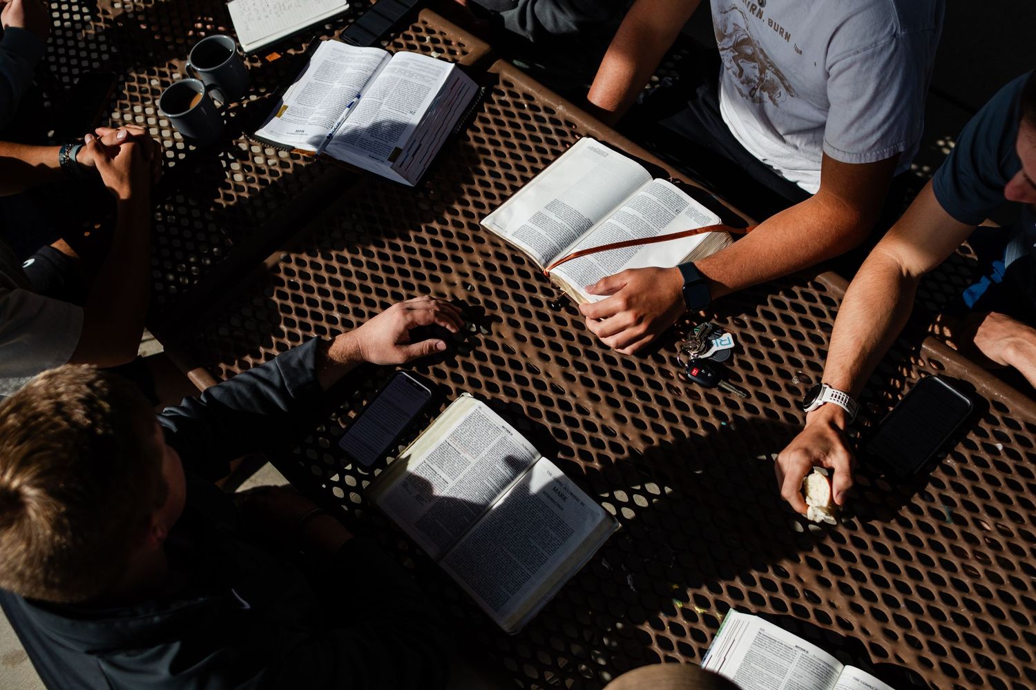 Students write and study together at desks in a classroom setting with papers spread out on dark patterned carpet.