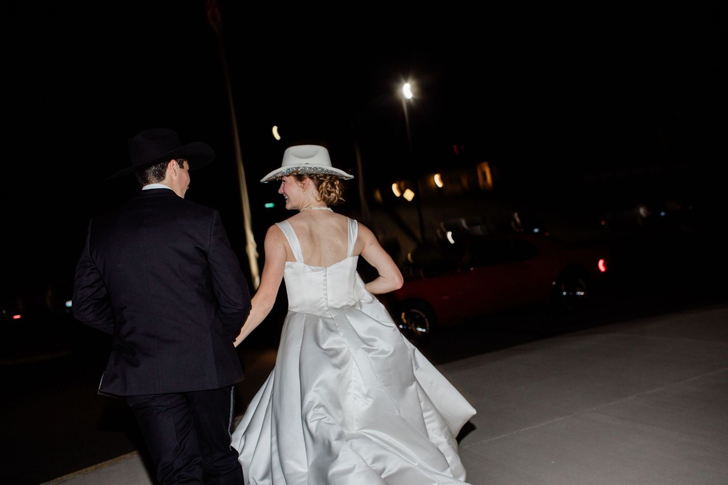 People walking outside at night with formal attire visible in dim lighting.