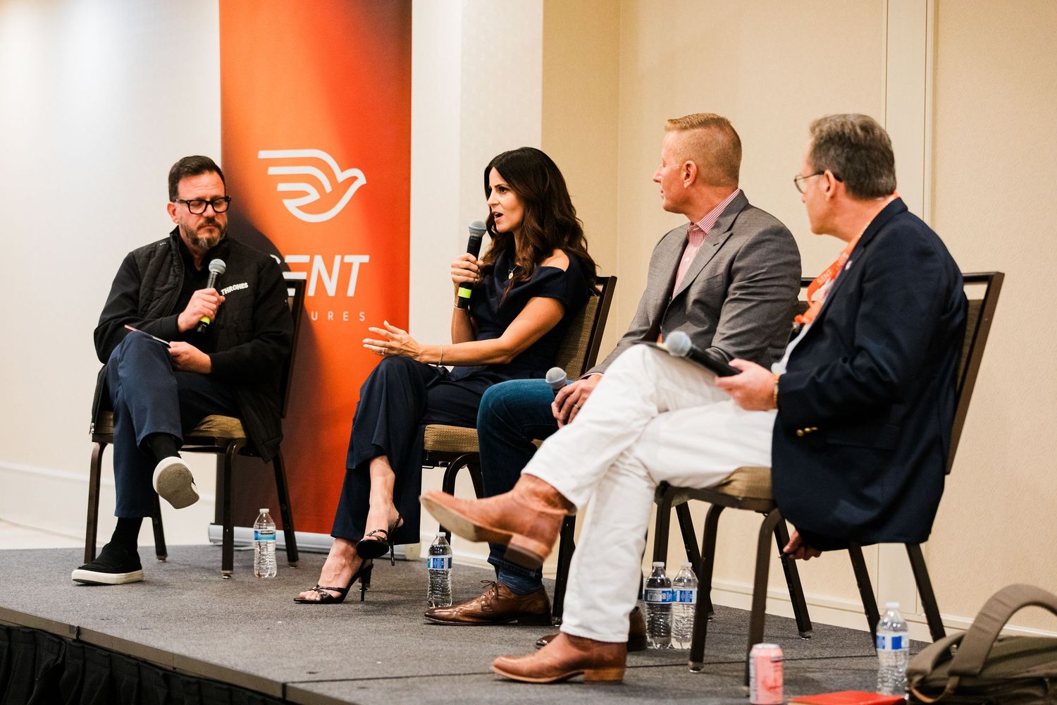 Four professionals engaged in a panel discussion at a ENT conference event, seated in chairs on a stage.