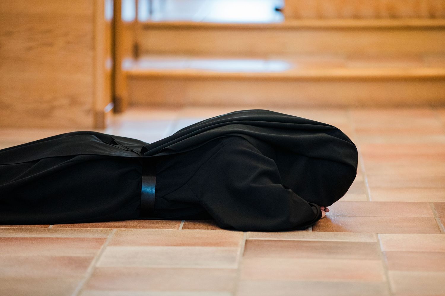 Black guitar case lying flat on a light tile floor near wooden furniture.